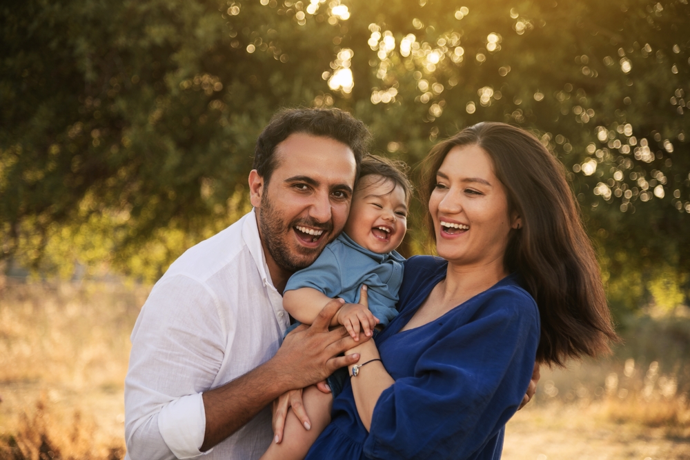 dental veneers in Allen Oak Point Dental in Allen Dentist in Allen husband and wife holding baby